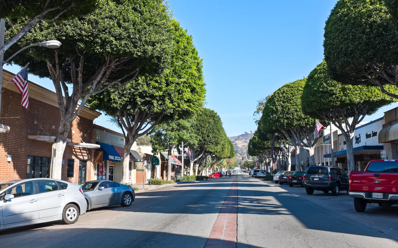 Greenleaf Avenue in downtown Whittier showing tree-lined street with storefronts and pedestrian walkway
